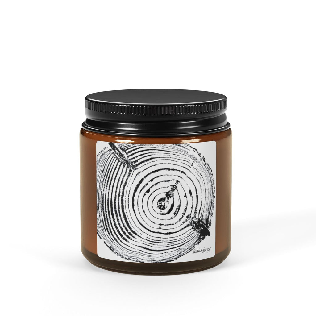 Candle jar with black lid and label featuring tree ring design on a white background